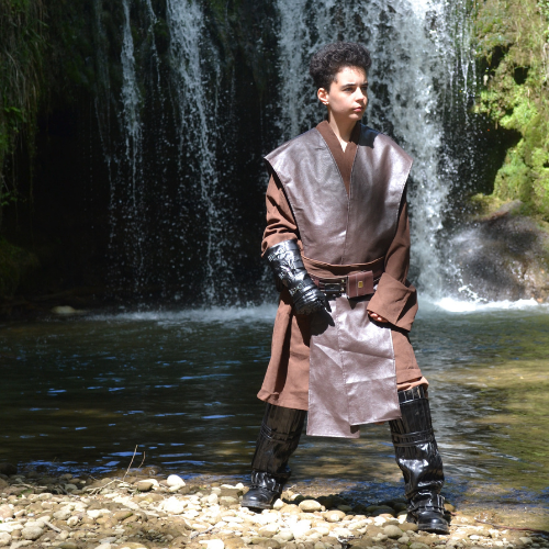 On voit sur l'image une personne en cosplay d'Anakin Skywalker. A l'arrière plan, on voit une étendu d'eau avec une cascade.